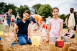 Two children play in the sand at a beach-themed activity day in a Hull Park.