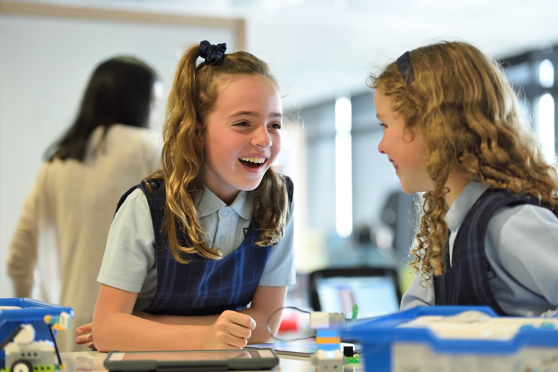 Two school pupils in uniform sat at a desk.