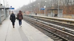 Two young people walk along a railway platform