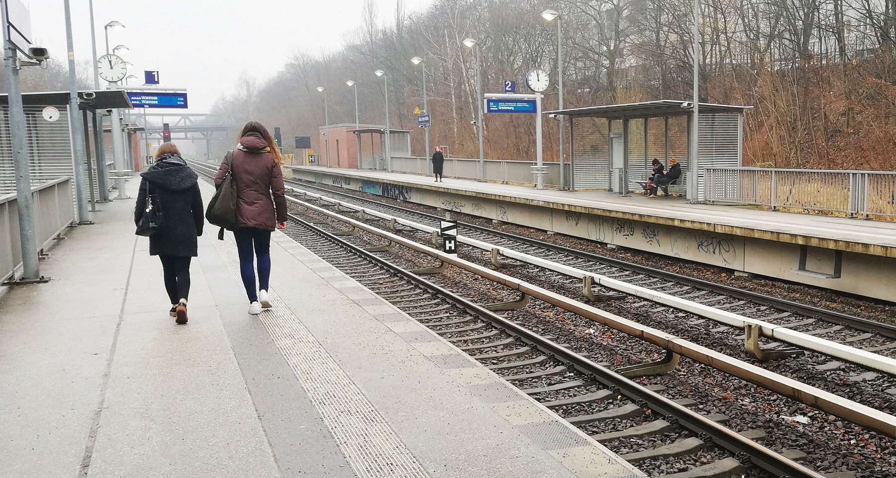 Two young people walk along a railway platform