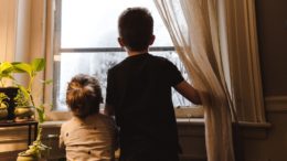 Two children look out of a window.