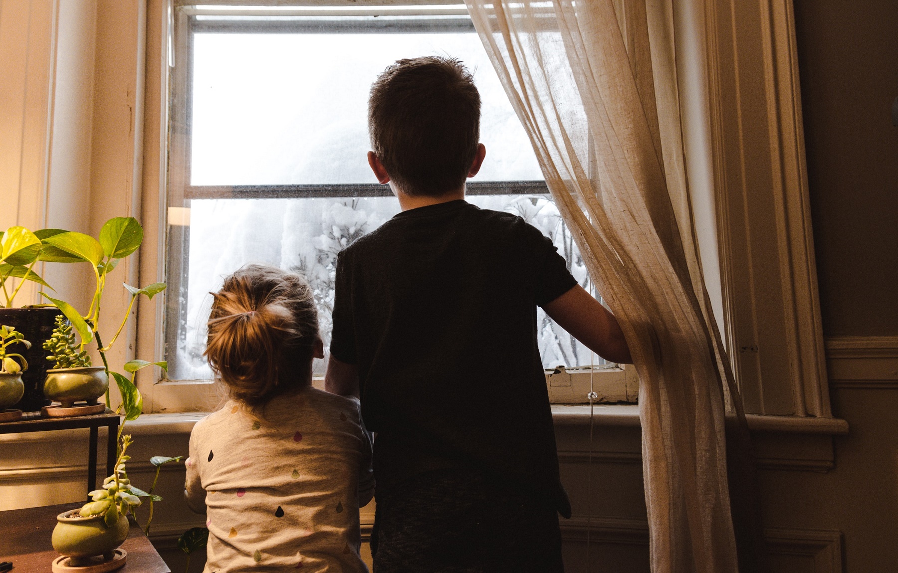 Two children look out of a window.