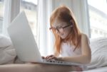 A girl with glasses using a laptop.