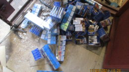 Packets of counterfeit cigarettes and tobacco sit on a concrete floor after being recovered from beneath a concrete floor