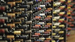 a large number of wine bottles are displayed in racks. Only their necks are visible