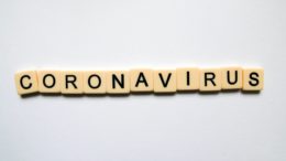 tiles from the game 'Scrabble' spell out the word 'Coronavirus' on a light grey background