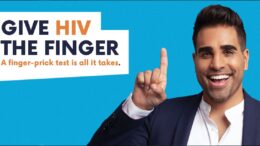 Celebrity Doctor Ranj Sing poses in front of a plain blue background. He is smiling and pointing to bright orange and blue text, which says: Give HIV the finger. A finger-prick test is all it takes