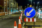 A road in England at night with traffic cones and signage for roadworks