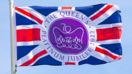 A flag commemorating the Queen's Platinum Jubilee, flying over a clear blue sky.