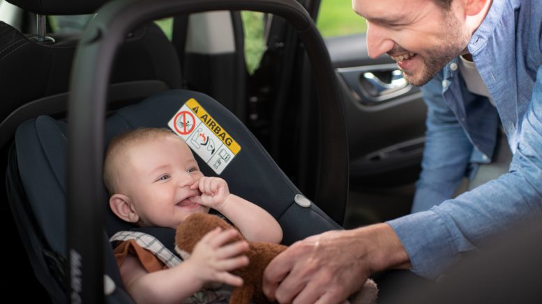 A parent with infant in car seat