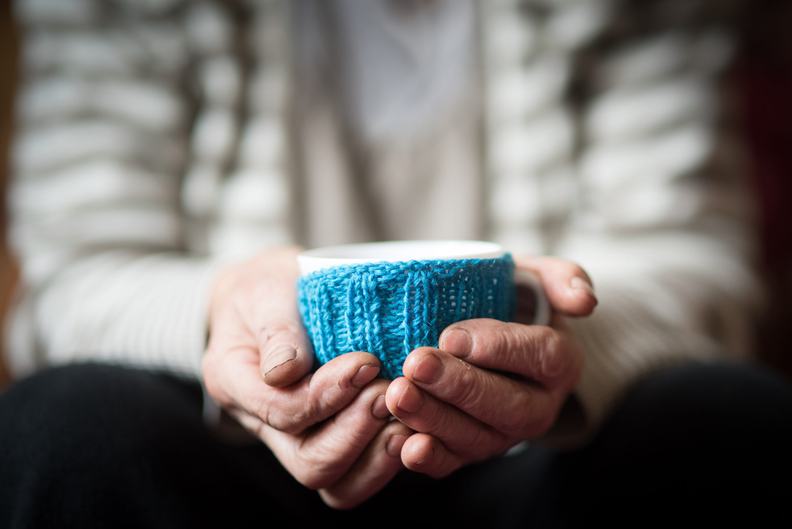 Elderly woman holding cup of hot coffee or tea