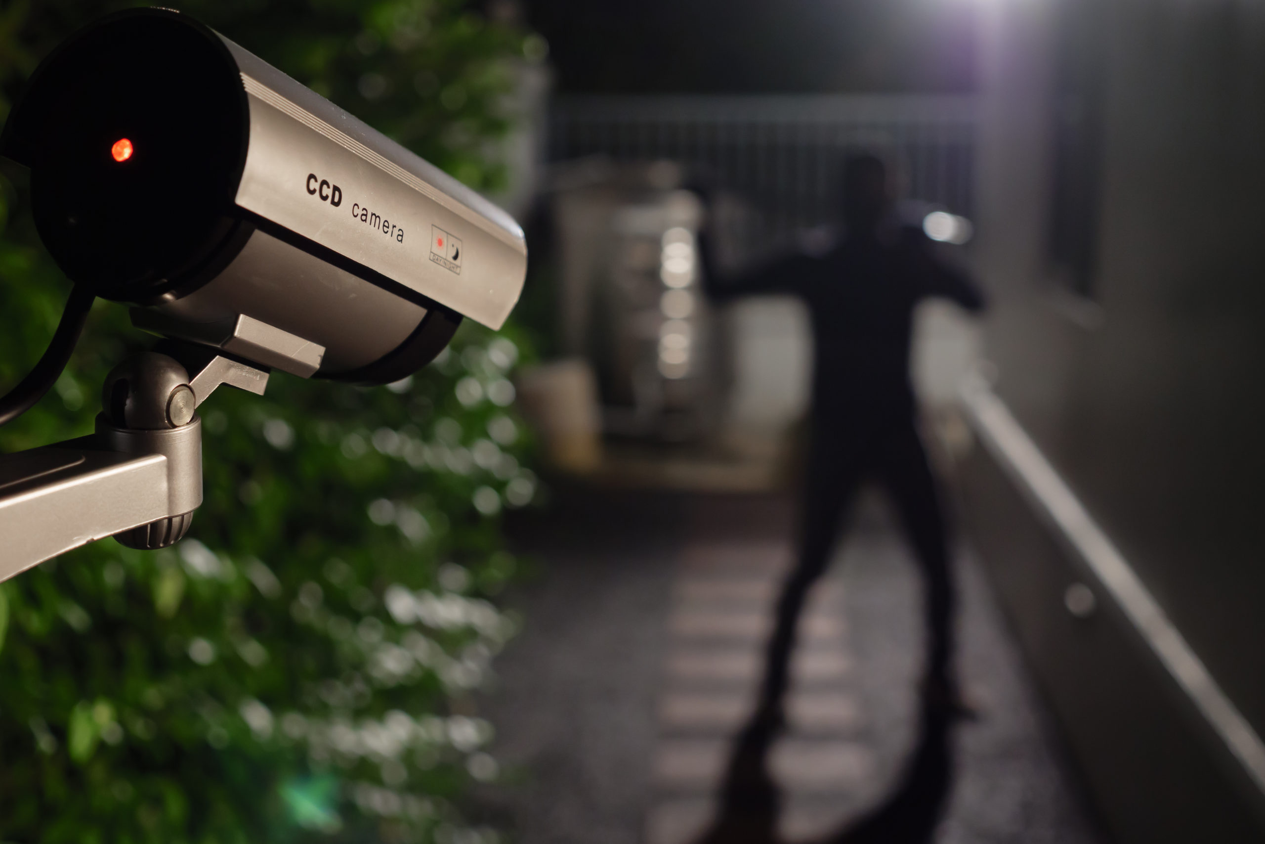 Posed image of a CCTV camera capturing a thief breaking into a house during the night