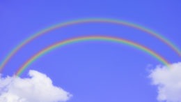 An illustration of a double rainbow with clouds either end, in a blue sky