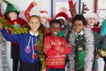 A group of children wearing Christmas jumpers and tinsel