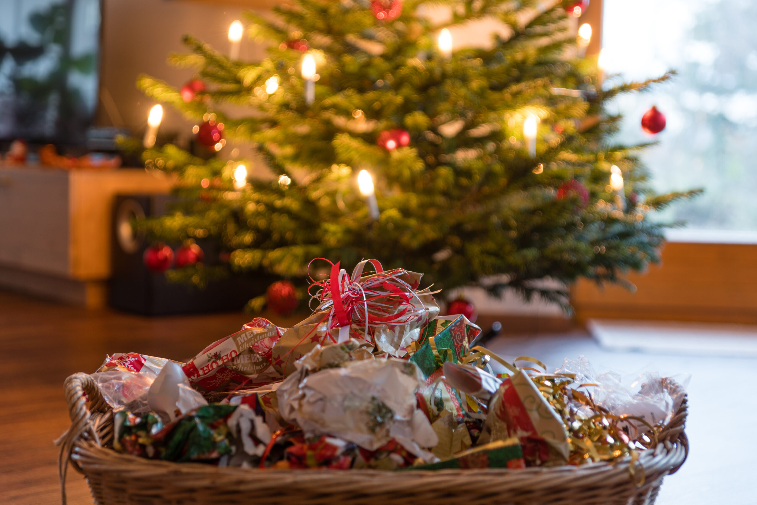 Used wrapping paper in a wicker basket in front of a Christmas tree