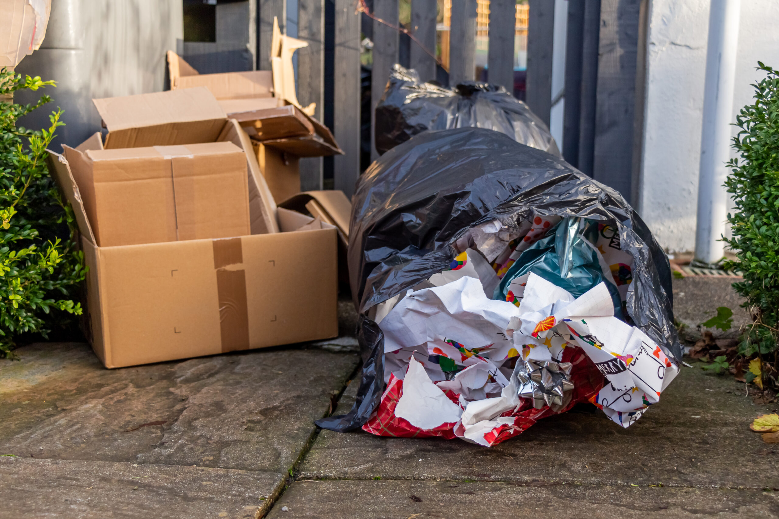 Christmas household waste consisting of boxes and wrapping paper, beside a bin