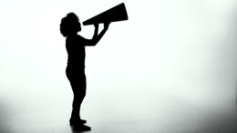 a black-and-white silhouette image of a person holding a large megaphone