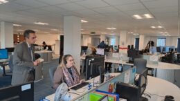An open plan office, which serves as thew Hull City Council call centre. council leader Mike Ross stands behind a call handler, who is working at a screen with a headset on