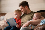 A man with a boy and a baby sat on the sofa together.