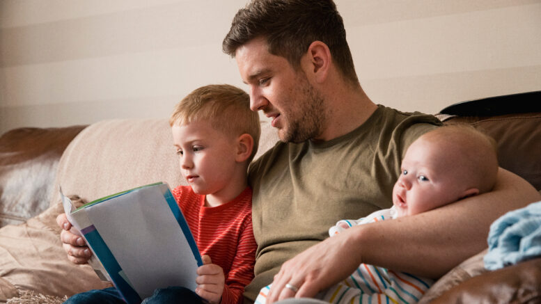 A man with a boy and a baby sat on the sofa together.