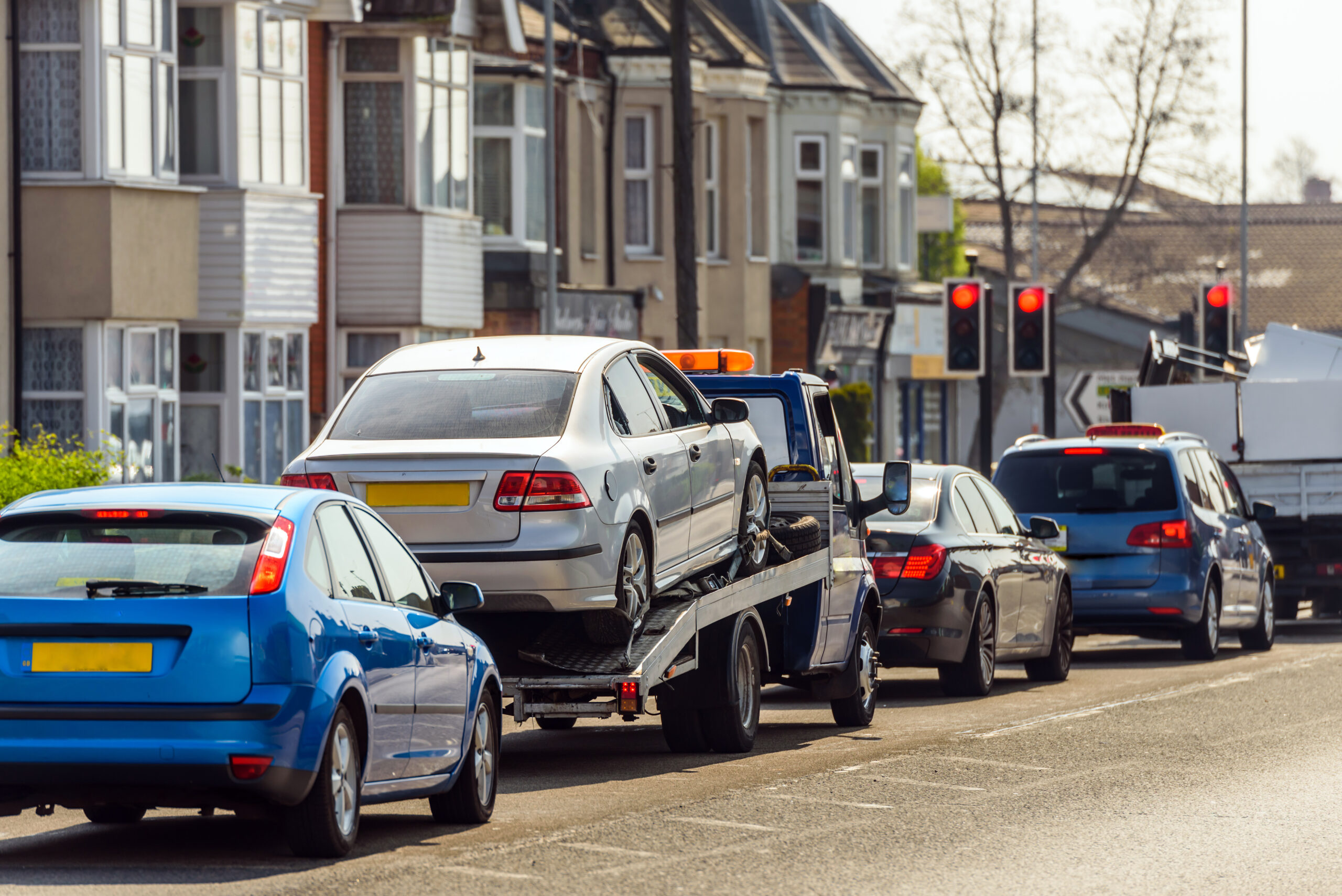 tow truck delivers damaged vehicle staying on red traffic light in english city