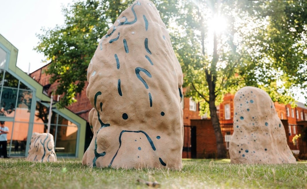Large stone coloured mountain shaped sculptures in an open space with trees.