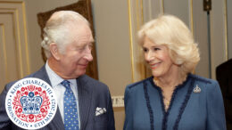 King Charles III and Queen Consort Camilla smiling with royal coronation logo in bottom left corner