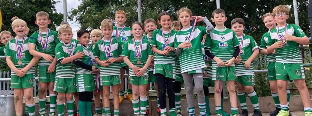 A group of young children in rugby kit, most of them are smiling
