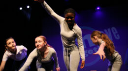 4 young female dancers dressed in grey pose on stage