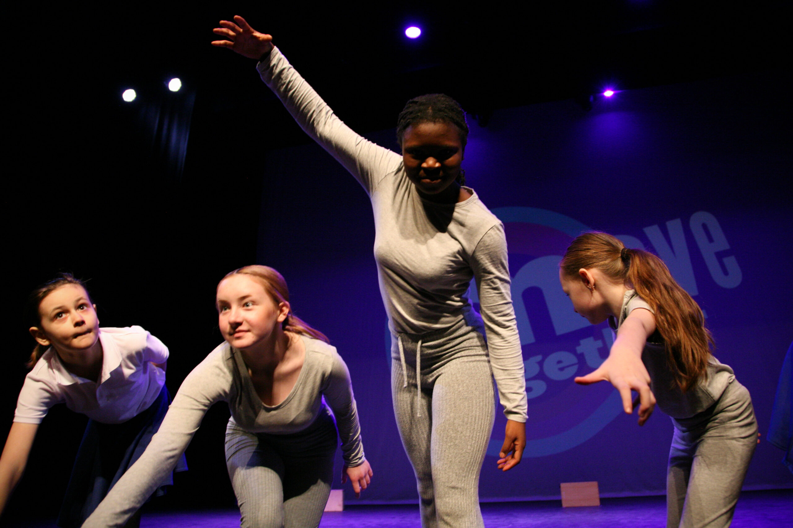 4 young female dancers dressed in grey pose on stage