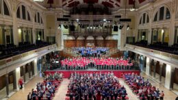 It is an image of the interior of Hull city hall, with hundreds of people singing