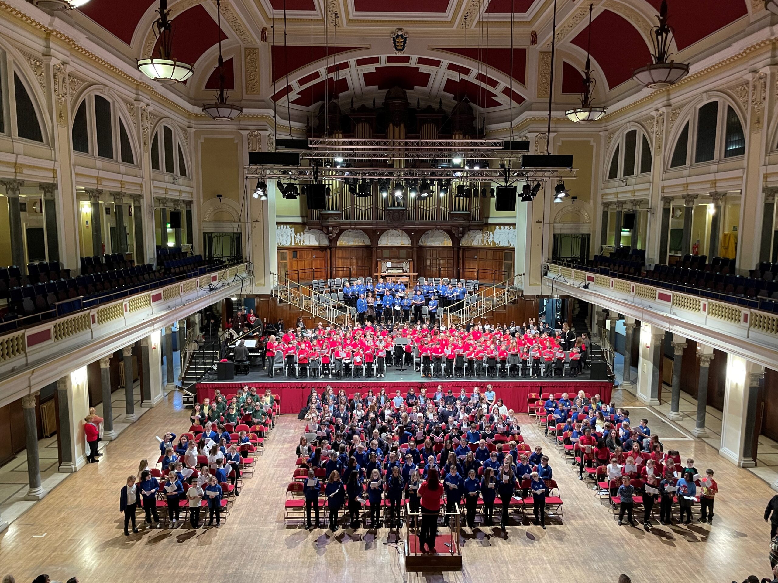 It is an image of the interior of Hull city hall, with hundreds of people singing