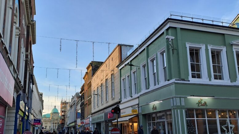 Christmas lights strung across street between buildings and shops