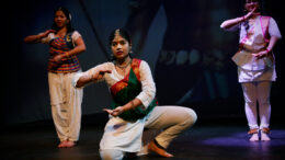 three female dancers in Indian dance costumes pose on stage