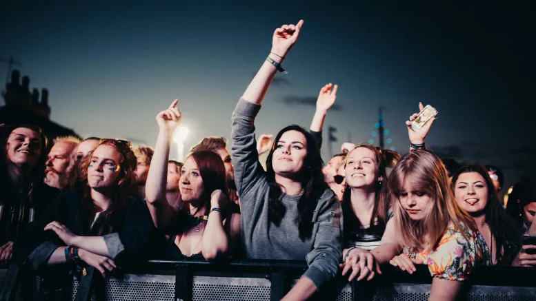 A crowd watching a stage with arms in the air