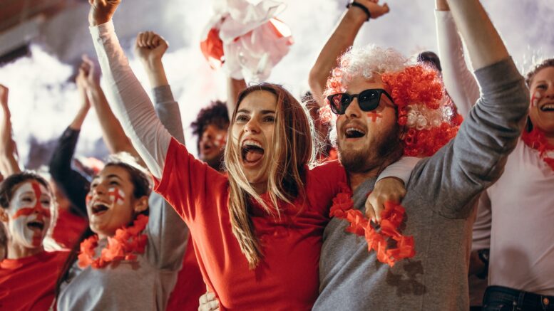 Young people watching football match chanting to cheer English national team.