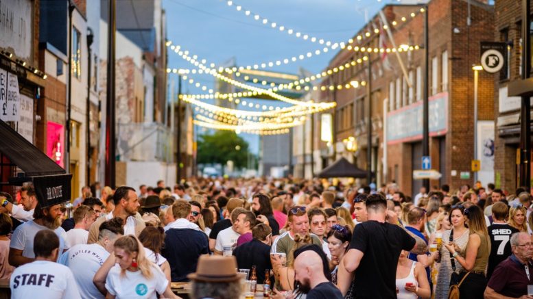 Hundreds of people crowded into a street with festoon lightings strung above