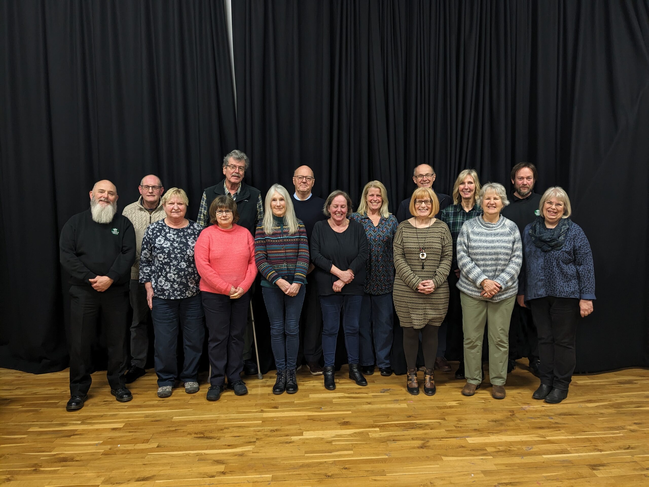 A group of people stand together against a black background