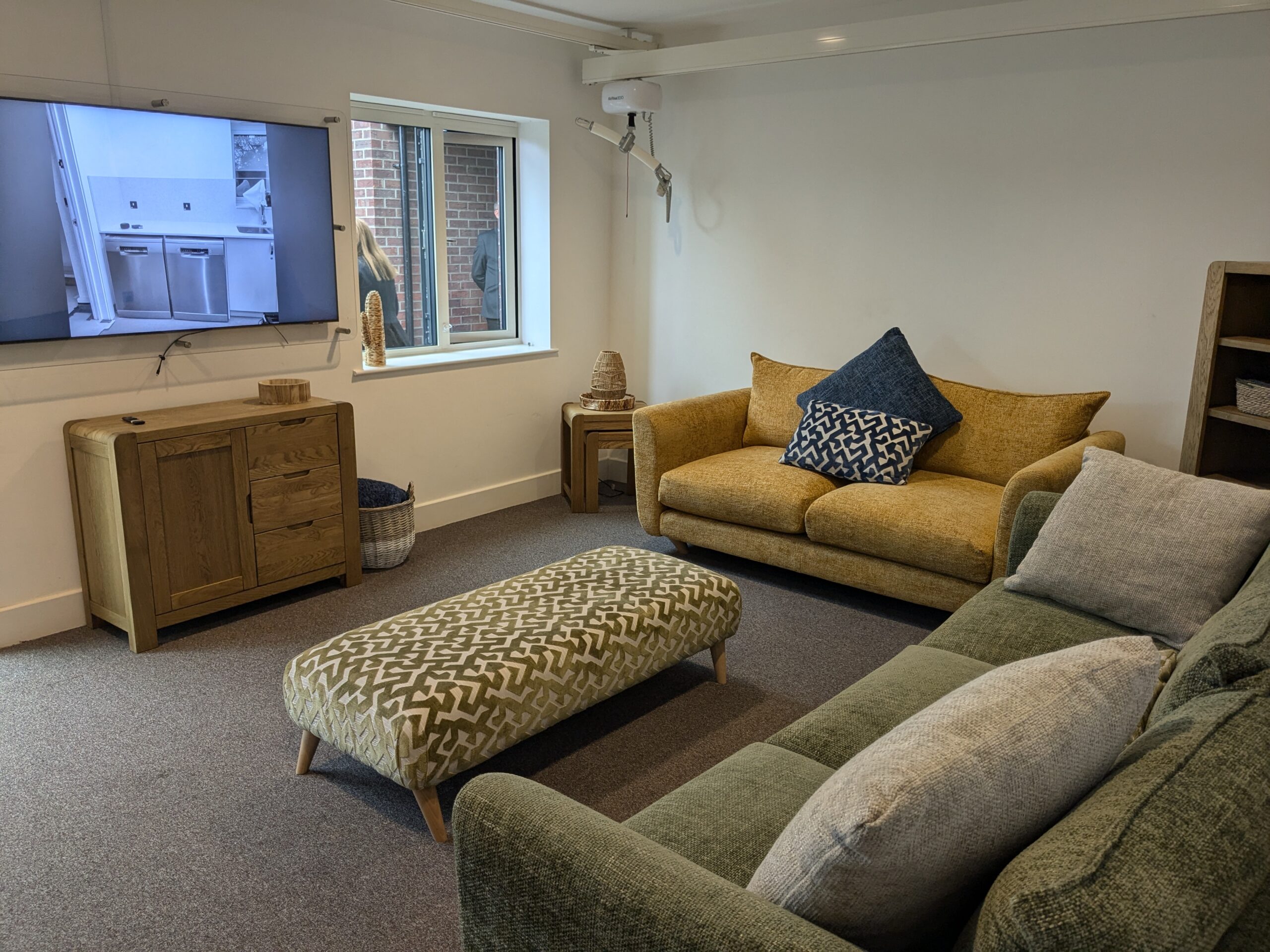 The living room has a yellow sofa and a green sofa, with a TV and patterned foot stool.