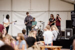 a band plays on a stage outdoors, in front of an audience