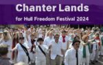 A group of singers all dressed in white shirts walk down a street.