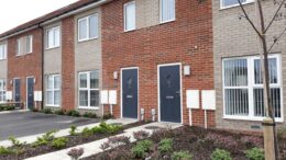 An image of newly-built terraced houses in Hull. They have blue doors and front gardens which are newly-planted.