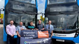 Stagecoach staff stood by two buses with a sign which reads Stagecoach Fostering Friendly.