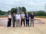 4 men and 2 women representatives from HCC, HCAL and Splash Pad Enterprises stand in front of a new splash pad with water jets spraying behind them