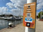 An orange sign on a lampost with Hull Marina in the background