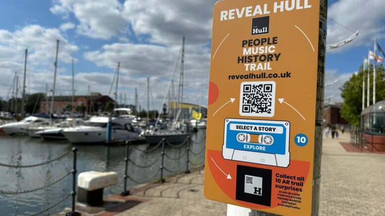 An orange sign on a lampost with Hull Marina in the background