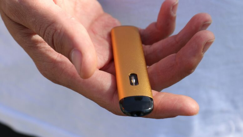 a close up of a person displaying a small vaping device on their outstretched palm