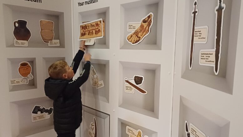 A boy at the new interactive wall at Museum of Archaeology.