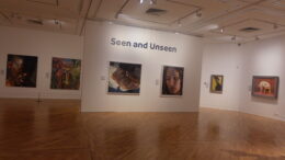 Image of white gallery walls with portrait paintings. 'Seen and Unseen' printed on wall