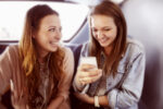 Two young women looking at a phone on the bus